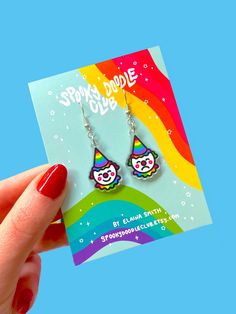 Welcome to the Spooky Doodle Circus! Step right up and embrace your playful side with these vibrant acrylic clown earrings! These eye-catching statement earrings are designed with high-quality, recycled acrylic and nickel-free metals, making them a lightweight rainbow dream!  Each earring features a unique clown design, one happy and one sad, symbolizing the duality of emotions. With charms measuring 1 inch long, these colorful clowns will add a touch of whimsy to any outfit, whether it's for a fun night out, a creative cosplay, or a festive celebration. Lightweight and comfortable to wear, these rainbow-colored clowncore earrings are sure to capture your colorful personality. The circus awaits! DETAILS: ~ printed on clear acrylic ~ 100% recycled acrylic  ~ the design is visible from both Clowncore Earrings, Clowncore Accessories, Clown Earrings, Circus Jewelry, Clown Design, Clown Pics, Creative Cosplay, Clown Core, Winona Mn