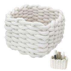 a white basket with two bottles in it next to a container that is made out of rope