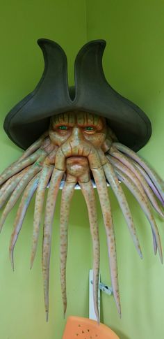 an odd looking face with long tentacles and a hat on it's head in a green room