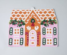 an embroidered house is shown on a white surface with red trimmings and green leaves