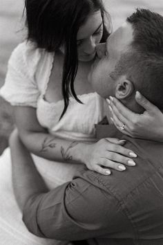 a man and woman kissing each other on the beach