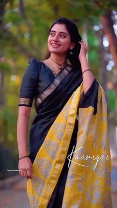 a woman in a black and yellow sari is posing for the camera with her hand on her head