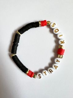 a black and red bracelet with gold letters on it that says, stay strong written in white letters