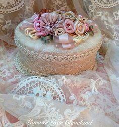 there is a small cake with pink flowers on the top and lace overlays