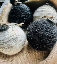 three balls of yarn are sitting in a basket on burlap fabric with twine