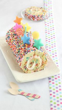 a piece of birthday cake with sprinkles and candles on a white plate