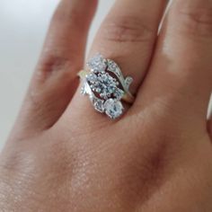 a woman's hand with a diamond ring on top of her finger and an engagement band