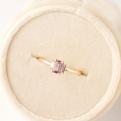 a pink tourmaline ring sitting on top of a white velvet cushioned box