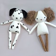 two stuffed animals made to look like they are holding each other's hands, one is wearing a dalmatian outfit