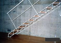 a set of stairs with wooden treads against a concrete wall in an empty room