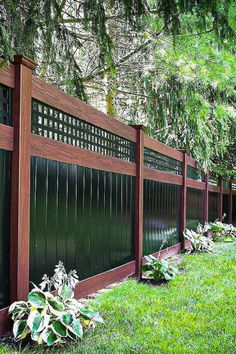 the fence is made of wood and has green grass in front of it, along with some trees