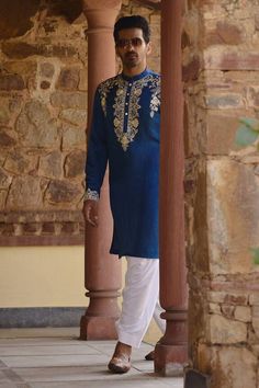 Blue kurta with thread embroidery along the placket. Paired with an ivory salwar. - Aza Fashions Traditional Indigo Kurta With Pallu, Ceremonial Sherwani With Zari Work In Chanderi, Ceremonial Raw Silk Kurta With Cutdana, Chanderi Sherwani With Zari Work For Traditional Ceremonies, Navratri Chanderi Sherwani With Intricate Embroidery, Ceremonial Raw Silk Churidar With Chikankari Embroidery, Navratri Sherwani With Intricate Embroidery In Chanderi, Transitional Blue Kurta For Traditional Ceremonies, Traditional Blue Sherwani For Diwali