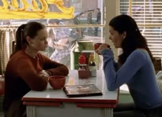 two women sitting at a table drinking coffee