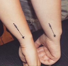 two people with matching tattoos on their hands holding each other's hand and one has an arrow in the middle