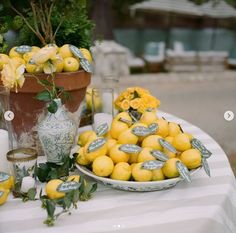 a table topped with lots of lemons next to a vase filled with yellow flowers