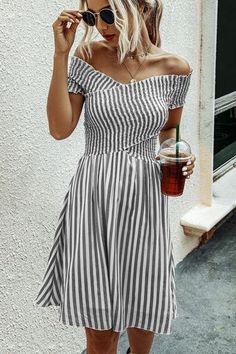 a woman in a striped dress holding a drink