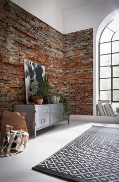 a living room with brick walls and rugs on the floor in front of it