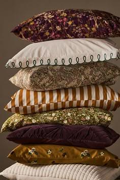 a stack of pillows sitting on top of each other in front of a gray background