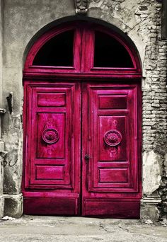 an old red door in front of a stone building with arched doorway and brick wall