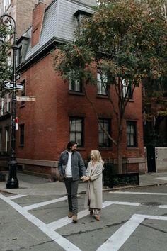 a man and woman standing in front of a red brick building on a city street