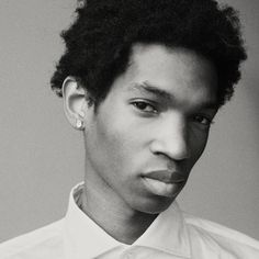 a black and white photo of a young man with curly hair wearing a dress shirt