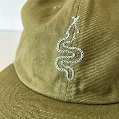 a green hat with a white snake embroidered on it