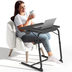 a woman sitting in a chair holding a cup and looking at her laptop