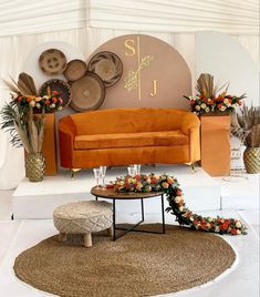 an orange couch sitting on top of a rug in front of a wall with flowers