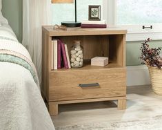 a nightstand with books and flowers on it in a bedroom next to a bed or window