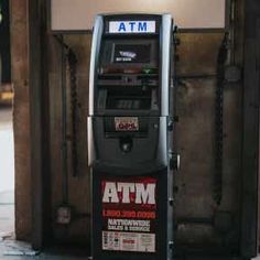 a atm machine sitting on the side of a street next to a building with a sign that reads mta