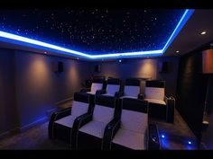 an empty home theater with black leather seats and blue lights on the ceiling is shown