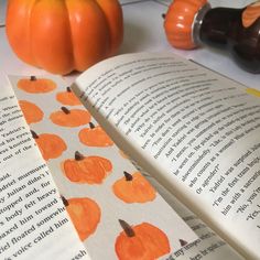 an open book with orange pumpkins on it and some other items next to it