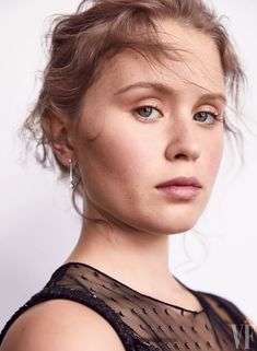 a close up of a person wearing a black dress and posing for the camera with her hair in a bun