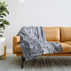 a couch with a blanket on it next to a potted plant