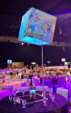 a room filled with tables and chairs covered in purple linens, lit up by colorful lights