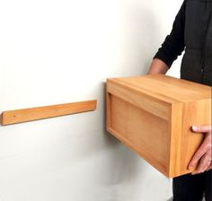 a person holding a wooden object in front of a white wall with a black jacket on