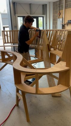 a man working on some wooden furniture in a room filled with chairs and other items