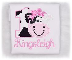 a cow with a pink bow on it's head and the number 1 is for a girl