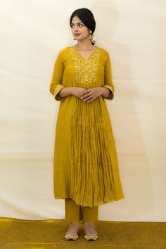 Mustard malai chanderi tunic with mirror, resham and zardosi hand embroidered yoke and cuffs. Comes with slim-fit pant and a slip.
Components: 3
Pattern: Hand embroidered
Type Of Work: Mirror, Resham, Zardosi
Neckline: Tunic : V Neck, Slip : Round
Sleeve Type: Tunic : Three quarter, Slip : Sleeveless
Fabric: Malai chanderi, Lining : Mulmul
Color: Yellow
Other Details: 
Closure : Back button
Disclaimer : The natural imperfection and textures in the weaves are the outcome of handloom fabrics (not Festive Straight Kurta Tunic With Zari Work, Anarkali Tunic Kurta With Mirror Work, Anarkali Style Kurta With Mirror Work, Festive Cotton Silk Tunic Kurta, Festive Anarkali Tunic Palazzo Set, Festive Anarkali Tunic Straight Kurta, Designer Tunic Set With Mirror Work, Festive Straight Kurta Tunic For Wedding, Festive Anarkali Tunic For Festivals