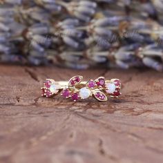 two gold rings with pink and white stones on top of a wooden table next to lavender flowers