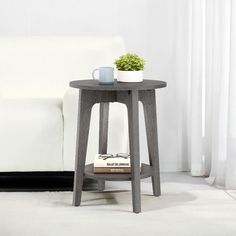 a small table with a book and cup on it in front of a white couch