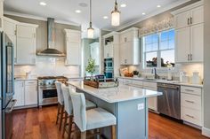 a large kitchen with white cabinets and stainless steel appliances in it's center island