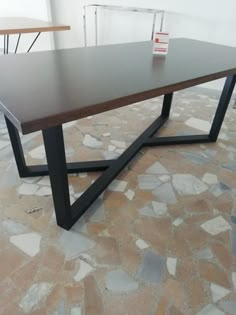 a table that is sitting on some kind of stone floor with two chairs in the background