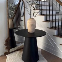 a vase sitting on top of a table next to a stair case