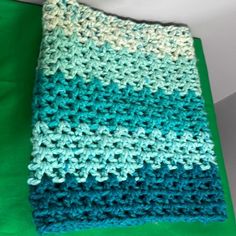 a blue and green crocheted blanket sitting on top of a table