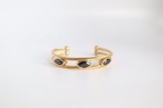 This Gold With Black Stone Stations Cuff Bracelet is a stunning addition to any jewelry collection. Crafted with high-quality gold and adorned with sleek black stones, this cuff bracelet adds a touch of elegance and sophistication to any outfit. Each stone is perfectly placed to catch the light, creating a dazzling effect that will surely turn heads. Elevate your style with this timeless and versatile bracelet. Classic Black Cuff Bracelet Bangle, Classic Black Cuff Bracelet In Bangle Style, Formal Black Bangle, Classic Black Bangle As Gift, Elegant Black Bracelet With Strap, Elegant Black Bracelets, Elegant Black Bangle Bracelet, Elegant Black Jewelry With Bracelet Strap, Formal Black Bangle Bracelet