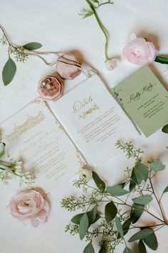 the wedding stationery is laid out on top of the table with flowers and greenery