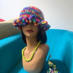 a mannequin wearing a multicolored hat and beaded necklace on top of a blue chair