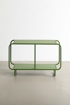 a green table sitting on top of a cement floor next to a white wall in an empty room