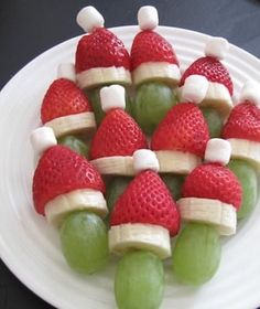 grapes and strawberries arranged in santa hats on a plate